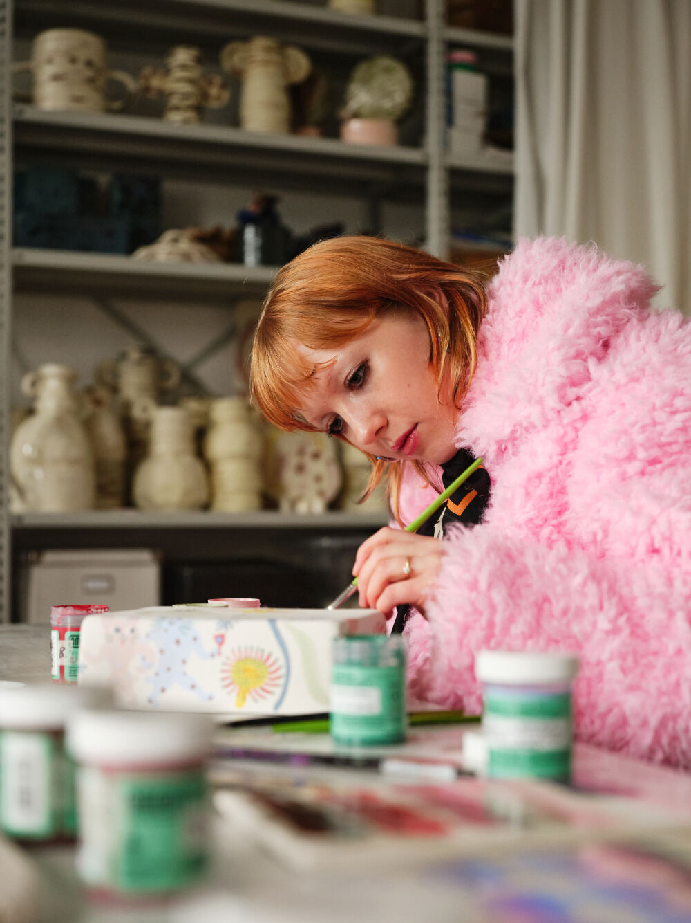 Yoyo Nasty in her artist studio painting a branded lunch box for the tech company Dreams